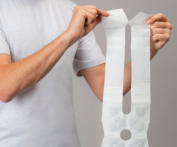 Eine Person trennt den ThermaCare Wärmeumschlag entlang der Perforation 