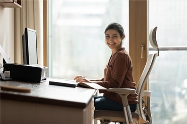 Eine Frau sitzt an ihrem ergonomisch ausgerichteten Schreibtisch