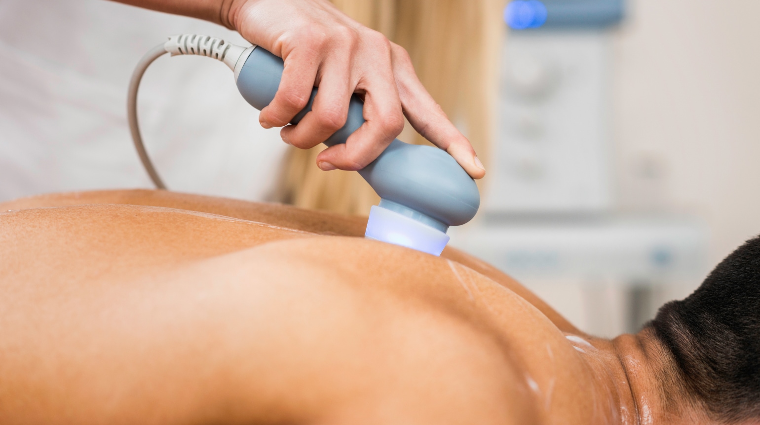 Ein Mann wird mit einem Ultraschnall-Geraet auf dem Ruecken behandelt