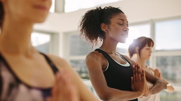 Frauen in einer Yoga Pose, mit den Händen vor der Brust.