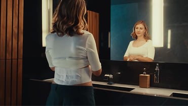 Eine Frau in einer stehenden Yoga-Position trägt unter ihrem T-Shirt einen ThermaCare Wärmegürtel