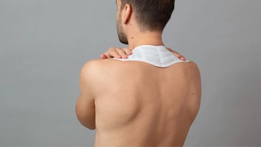 Ein Mann wendet einen Wärmeumschlag im Nackenbereich an