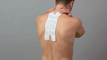 Ein Mann wendet einen Wärmeumschlag bei einem größeren Schmerzbereich am Rücken an