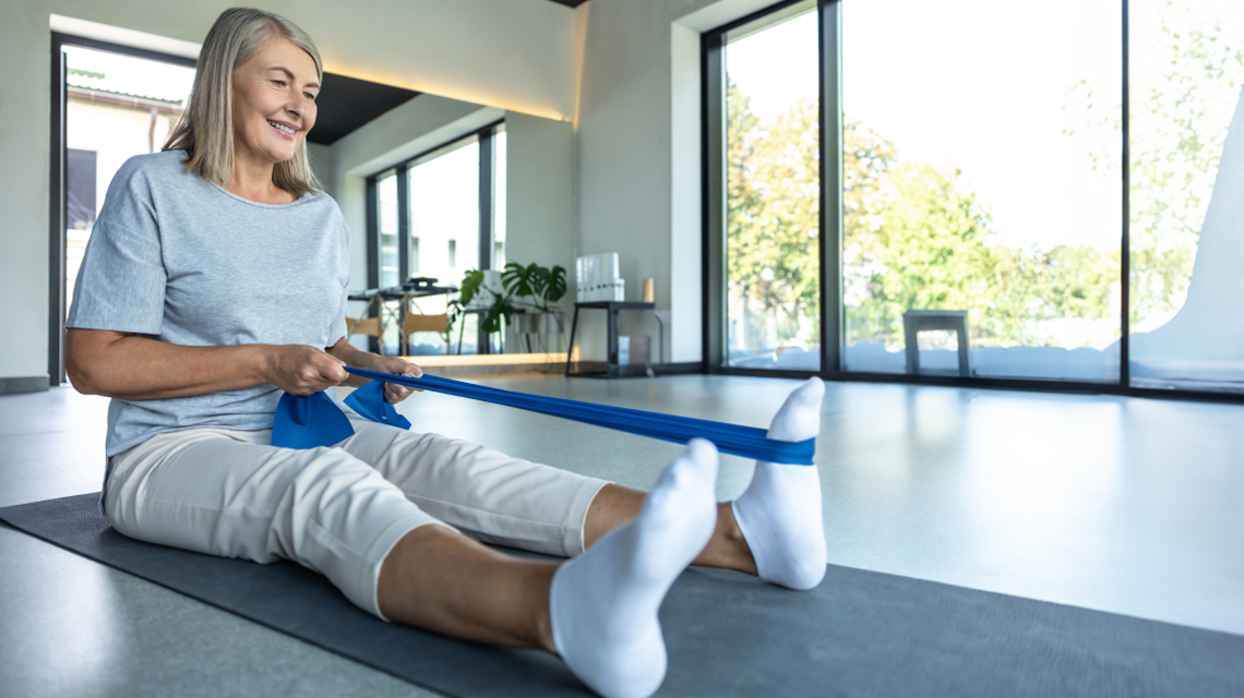 Eine Frau dehnt ihre Waden mit einem Fitnessband
