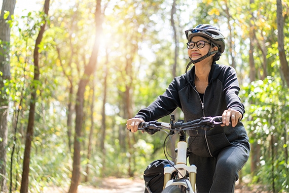 Eine Frau faehrt mit dem Fahrrad durch den Wald Eine Frau faehrt mit dem Fahrrad durch den Wald