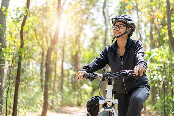 Eine Frau faehrt mit dem Fahrrad durch den Wald