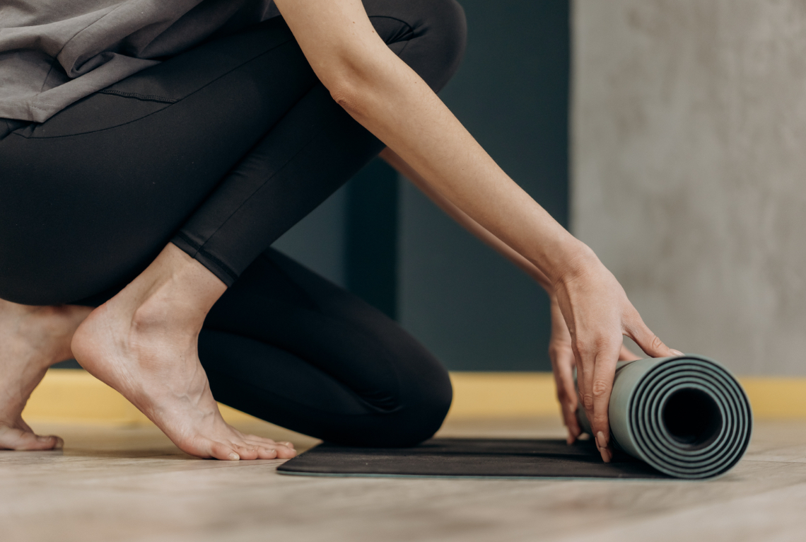 Frau rollt Yogamatte am Boden aus