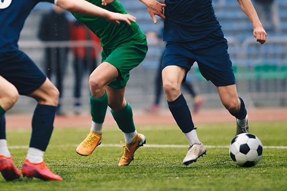 Die Beine von drei Personen beim Fußball Spielen