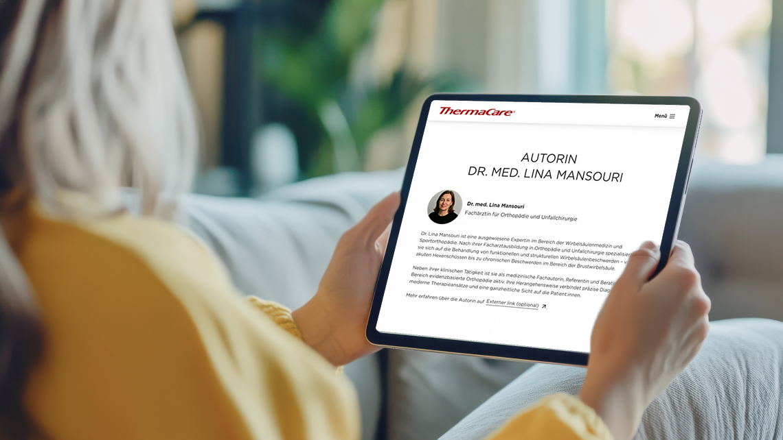 Person sitzt mit Tablet auf dem Sofa und surfed auf der ThermaCare Webseite