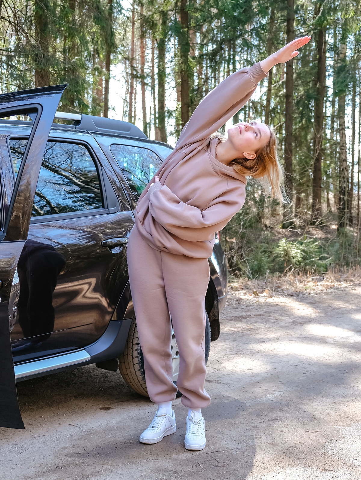 Eine Frau in braunem Trainingsanzug macht Dehnübungen