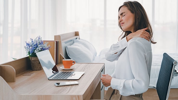 Frau hält sich im Homeoffice den Nacken