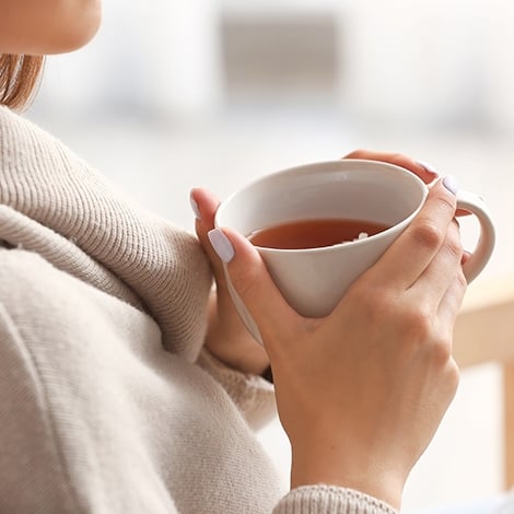 Frau hält eine Tasse Tee in den Händen