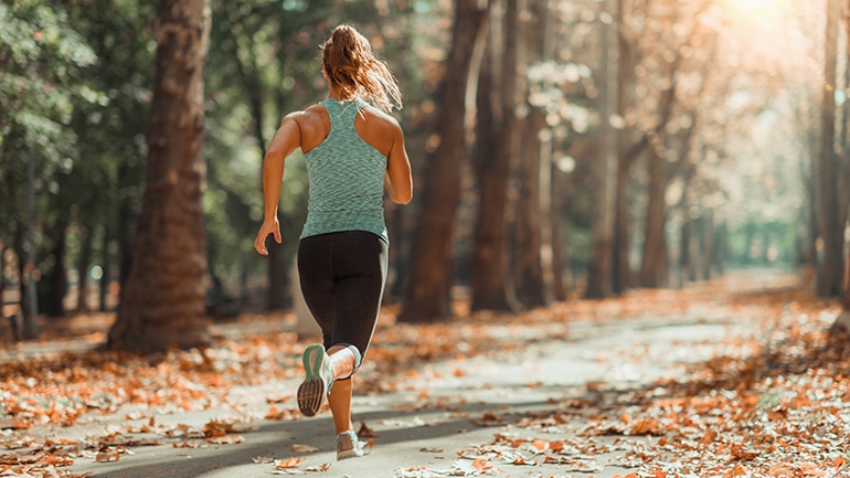 Frau joggt einen Waldweg entlang